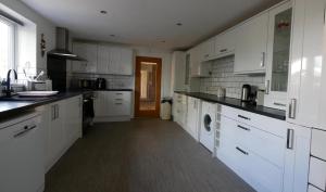 a large kitchen with white cabinets and black counter tops at Bright, Stylish 1-Bed Bungalow with Private Garden in Marton