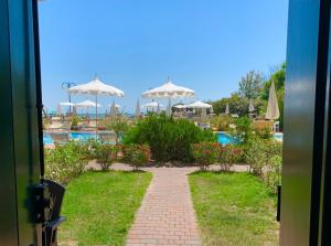 a walkway leading to a swimming pool with umbrellas at Eurobeach Residence in Cavallino-Treporti