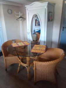 a dining room with a glass table and wicker chairs at Kleines Burgstübchen in Hundheim