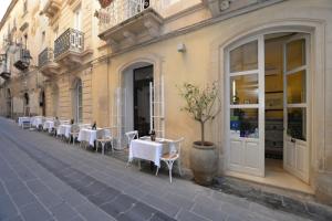 a restaurant with white tables and chairs on a street at Hotel Gargallo in Syracuse