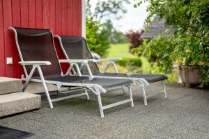 two empty chairs sitting next to a red building at Ferienhaus Waldfee in Reutin