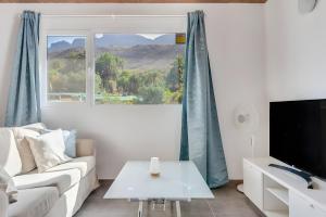 a living room with a white couch and a large window at Country House Near Fataga in Artedara