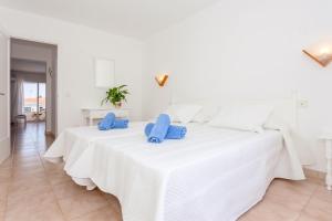 a white bedroom with a large white bed with blue pillows at Cala'n Blanes Park 228 in Cala en Blanes