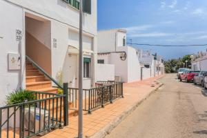 a street with white buildings and cars parked on the street at Cala'n Blanes Park 228 in Cala en Blanes