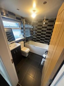 a bathroom with a tub and a toilet and a sink at Cosy 3 Bedroom in Birmingham in Birmingham