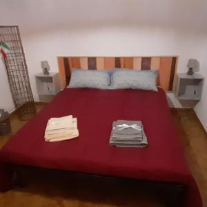 a red bed with two piles of towels on it at B e B Beglia Alguer in Alghero