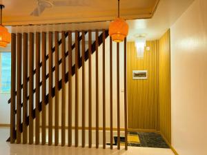 a hallway with a wooden staircase with a brown railing at Serenity Stay in Huraa