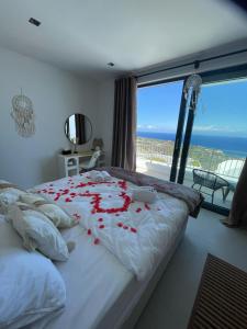 OrgaにあるRomantic Santorini-Style Villa with Private Pool and Sea Viewのベッドルーム1室(赤いバラの花びらが飾られたベッド1台付)