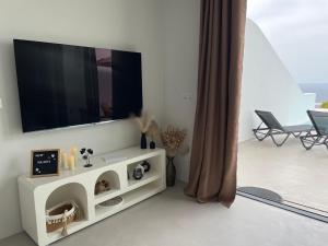 OrgaにあるRomantic Santorini-Style Villa with Private Pool and Sea Viewの壁にテレビが取り付けられたリビングルーム