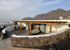 a house with a stone wall next to a mountain at Daidas Beach House - with hot whirlpool in Famara in Famara +36 photos