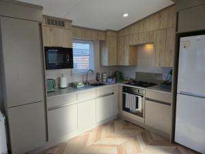 a kitchen with white cabinets and a white refrigerator at Baywood View Lodge in East Heslerton
