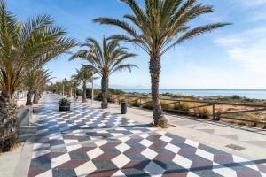 a sidewalk with palm trees and the ocean at Casa en la playa con piscinas 11 A in Puerto Marino