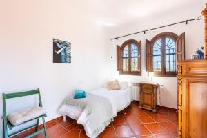 ein Schlafzimmer mit einem Bett und einem Stuhl darin in der Unterkunft Casa de los Sueños in Villanueva del Rosario