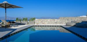 a swimming pool with a couch and an umbrella at ANOTERRA VILLAS -Auralis in Ambelas