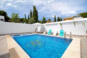 einen Pool mit blauen Stühlen und einer weißen Wand in der Unterkunft Casa Anna in Novo Sancti Petri