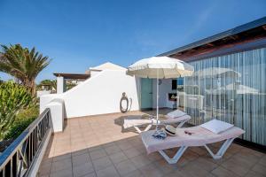 eine Terrasse mit 2 Liegestühlen und einem Sonnenschirm in der Unterkunft Casa Vista Hermosa in Playa Blanca