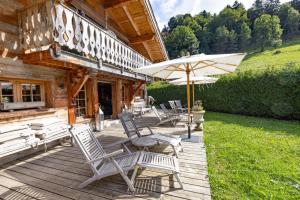 a wooden deck with chairs and an umbrella at Chalet Zibeline in Megève