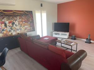a living room with a red couch and a tv at Maison Opuceb in Saint-Papoul