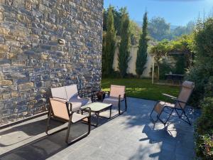 eine Terrasse mit Stühlen, einem Tisch und einer Steinmauer in der Unterkunft Jardin de los Pirineos- Margas Golf in Sabiñánigo
