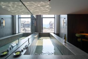 een badkamer met een zwembad met twee wastafels bij 乐山L私汤江景酒店乐山大佛店leshan in Leshan +34 foto's