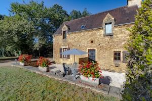 ein Steinhaus mit einem Sonnenschirm und Blumen davor in der Unterkunft Le Petit Pech in Le Sirey
