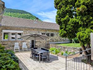 a patio with an umbrella and a table and chairs at Gîte le Marmare in Caussou