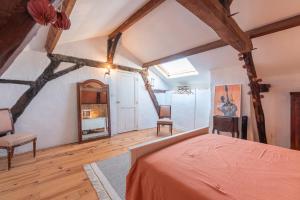 an attic bedroom with a bed and a chair at Maison Blousson, Longère gersoise in Malabat +24 photos