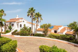 a large white house with palm trees and a driveway at Vistafaro in Es Mercadal