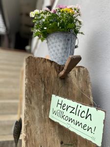 ein Blumentopf auf einem Baumstamm mit einem Schild in der Unterkunft Traumhaft Wohnen Im Haus Blum in Herbolzheim