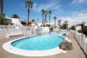 een groot zwembad in een resort met palmbomen bij Puerto Chico H in Playa Blanca