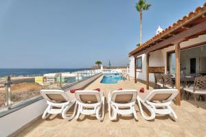 a patio with white chairs and a swimming pool at Villa Atlantico in San Miguel de Abona