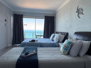 a bedroom with two beds and a view of the ocean at Lilies & Leopards B&B in Mossel Bay