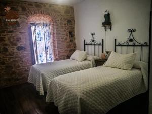 two beds in a room with a brick wall at HOTEL RURAL TOCAMPAVI in Chillón