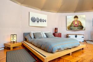 Un dormitorio con una cama grande con marco de madera. en Yurta Mongola Delta del Ebro, en Camarles