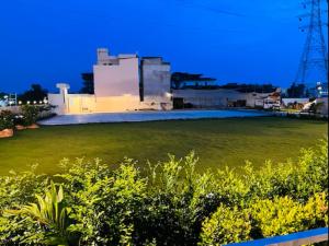 加雅DIVINE HOTEL AND RESORTS的一片大片草场,有一座建筑背景