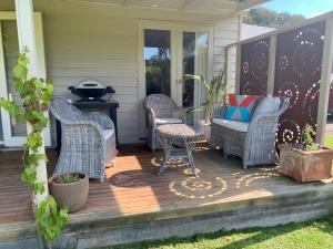a screened porch with wicker chairs and a table at A Bed & A Red @ Berry’s Creek in Berrys Creek