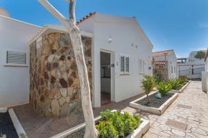a white house with a stone wall and some plants at Casa vista golf in Caleta De Fuste