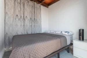 a bed in a white room with a curtain at Casa vista golf in Caleta De Fuste