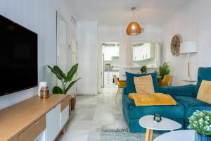 Una sala de estar con un sofá azul y un televisor en Doña Sofía, en Fuengirola