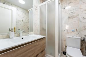 Un baño blanco con lavabo e inodoro. en Doña Sofía, en Fuengirola 16 fotos más