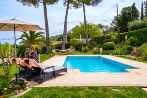a pool with a chair and an umbrella at Le Mas des Pins in Peymeinade