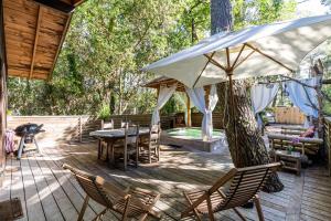 a patio with a table and chairs and an umbrella at Chalet Bangli in Lacanau