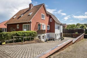 a red and white house on a cobblestone street at Ferienwohnung Heide 2 in Walsrode