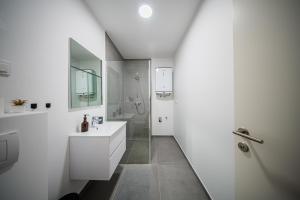 een witte badkamer met een wastafel en een douche bij Flex SelfCheckIns 188 - Zagreb - 2 Bedrooms - Parking in Zagreb
