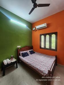 a bedroom with a bed with an orange and green wall at Le homestay villa in Puducherry
