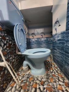 a bathroom with a blue toilet with a painting on the wall at Le homestay villa in Puducherry