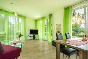 - un salon avec des murs verts, une table et des chaises dans l'établissement Ferienwohnung Orchidee, à Sipplingen