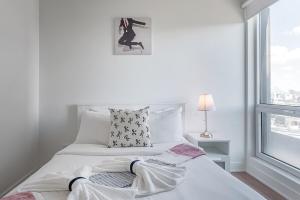 een wit bed in een witte kamer met een raam bij Downtown Montreal 1BR - Sleeps 4 in Montreal