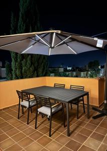 a table and chairs under an umbrella on a patio at Ático Jardín del Golf, Casa Alma in Chiclana de la Frontera