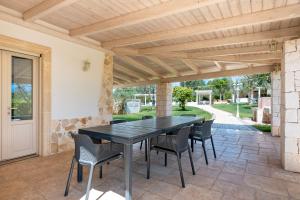 フランカヴィッラ・フォンターナにあるTrulli di Buontempoの木製のパーゴラの下に黒いテーブルと椅子